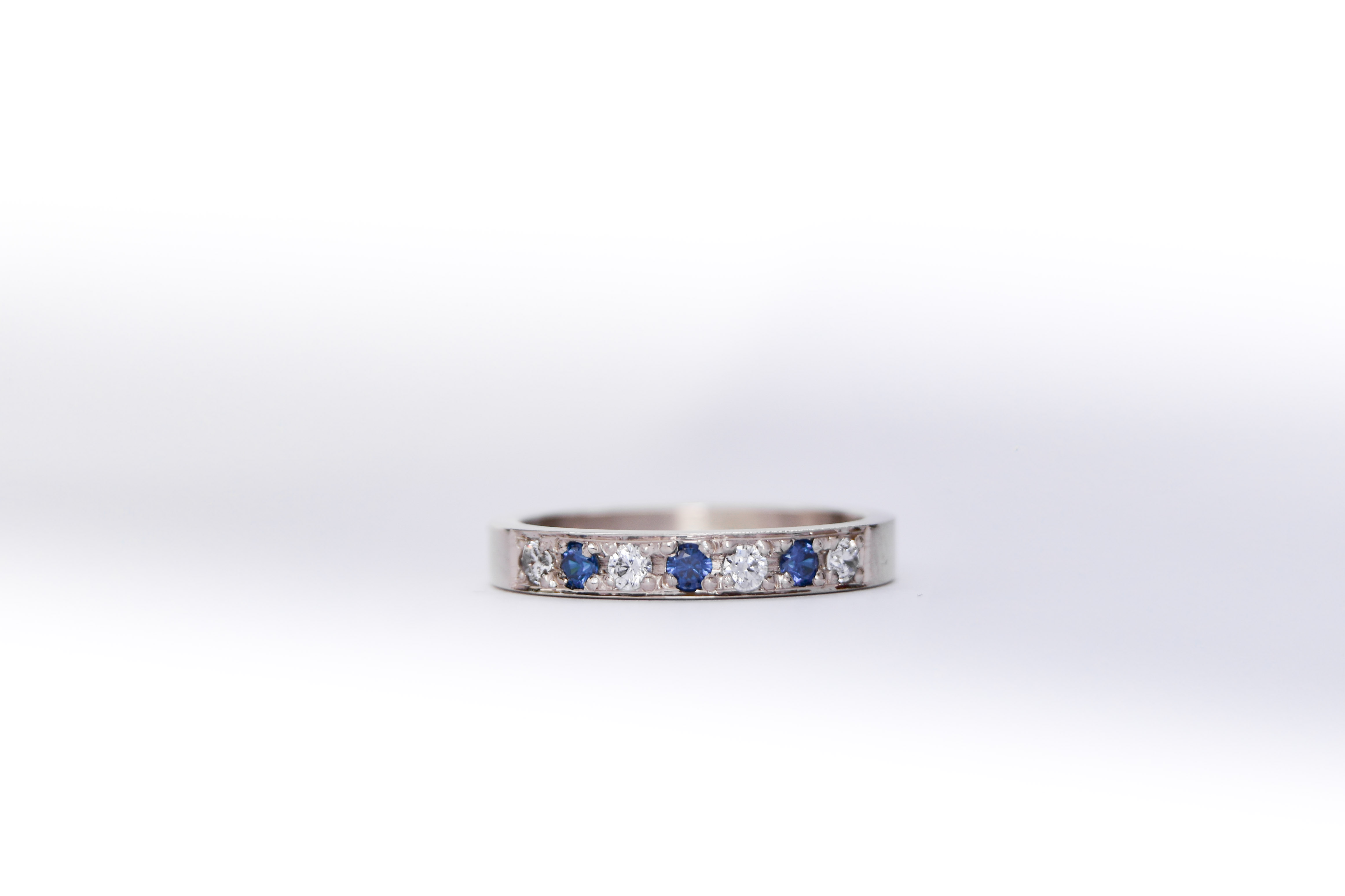 anillo de compromiso de oro 18k blanco medio sin fin con diamantes y zafiros sobre fondo blanco