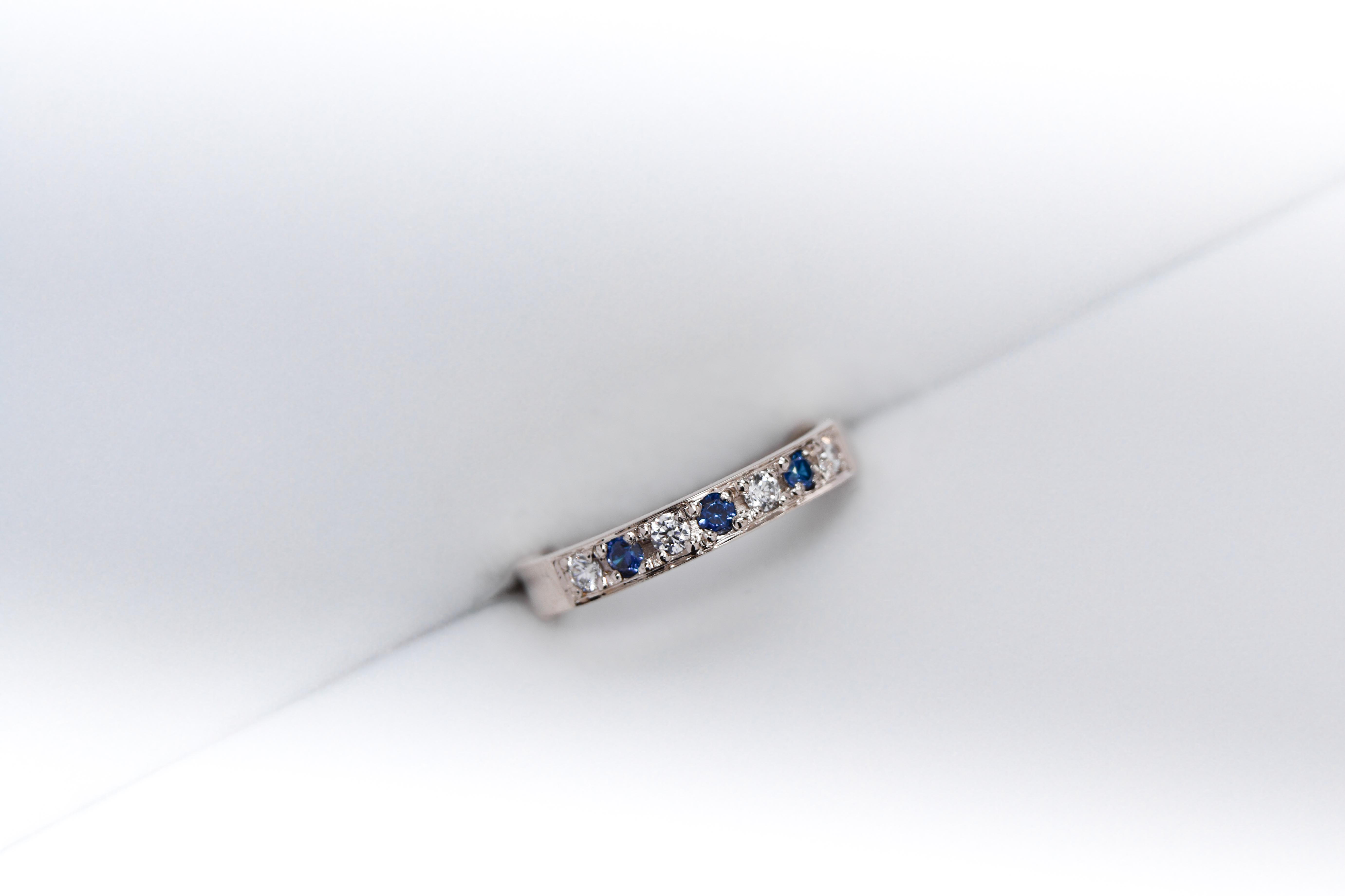 anillo de compromiso de oro 18k blanco medio sin fin con diamantes y zafiros sobre fondo blanco