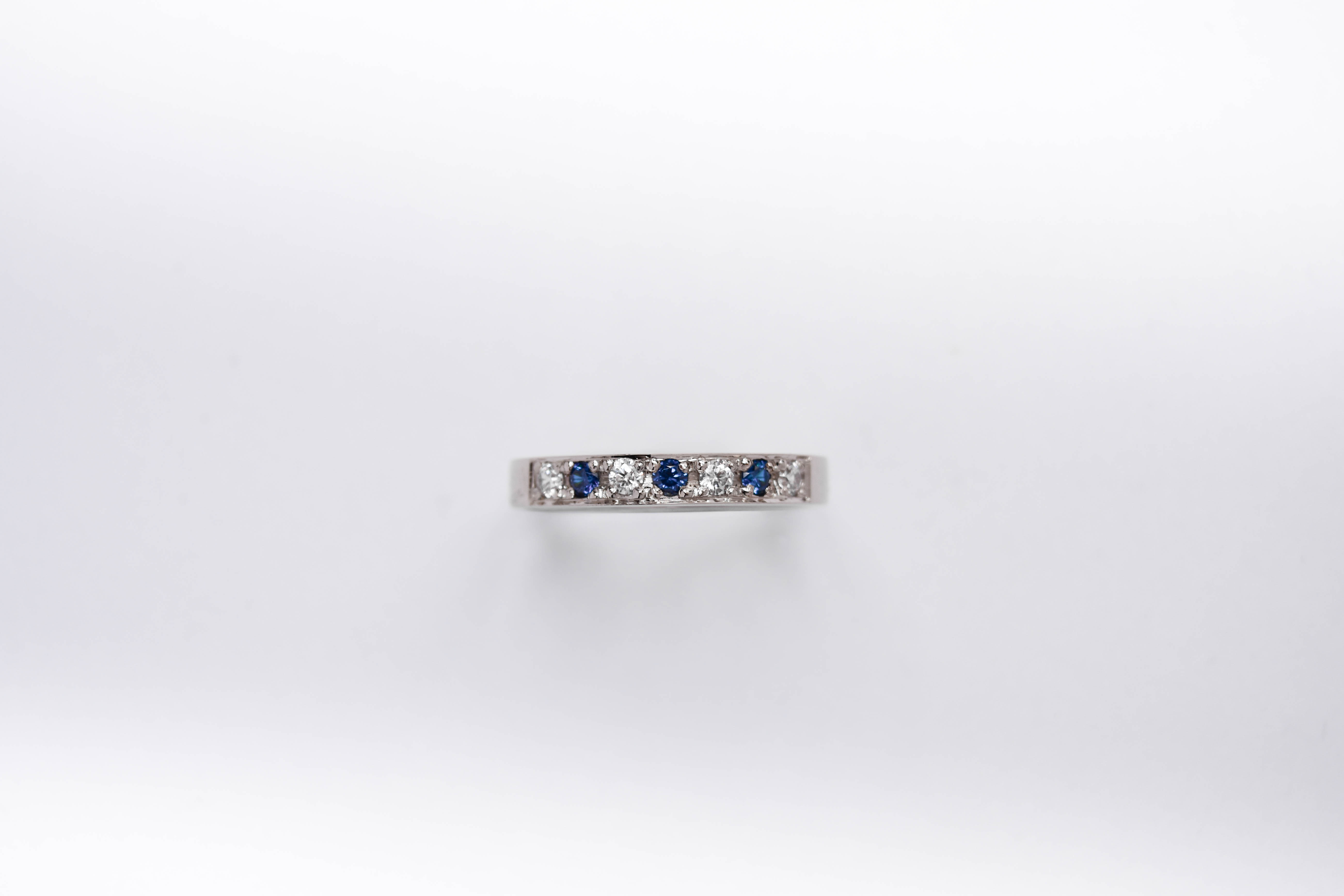 anillo de compromiso de oro 18k blanco medio sin fin con diamantes y zafiros sobre fondo blanco