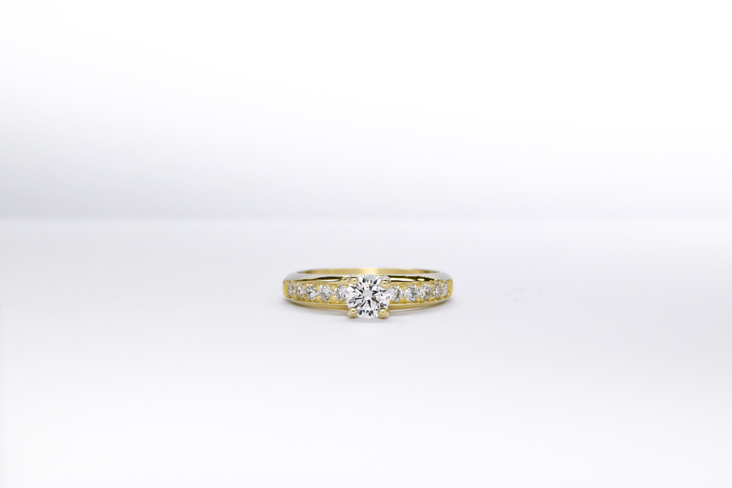 Anillo de compromiso de oro 18k amarillo con diamantes blancos sobre fondo blanco
