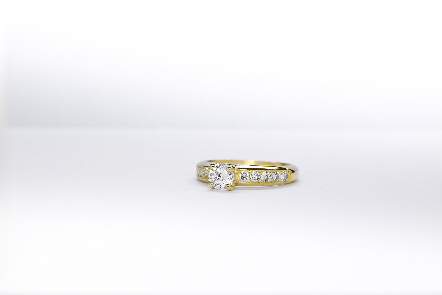 Anillo de compromiso de oro 18k amarillo con diamantes blancos sobre fondo blanco