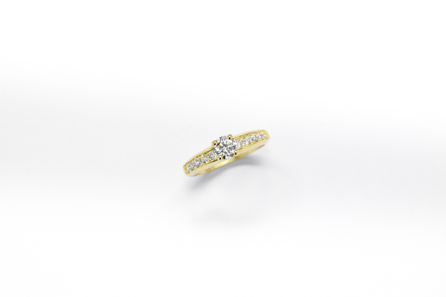 Anillo de compromiso de oro 18k amarillo con diamantes blancos sobre fondo blanco
