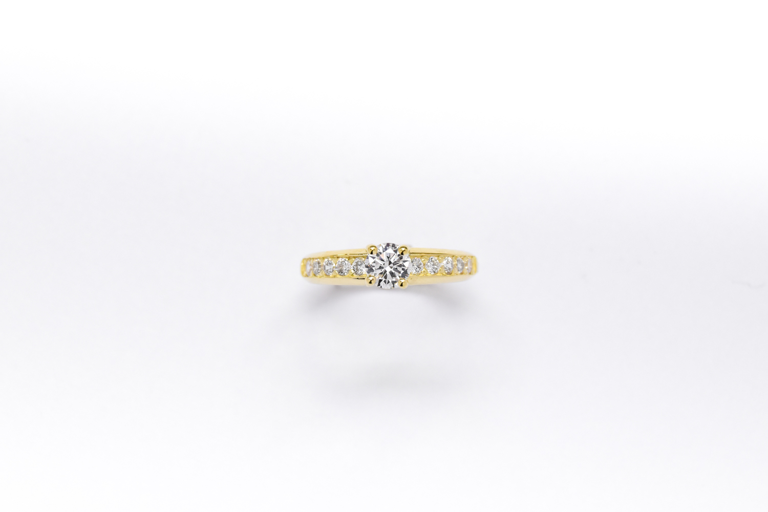 Anillo de compromiso de oro 18k amarillo con diamantes blancos sobre fondo blanco