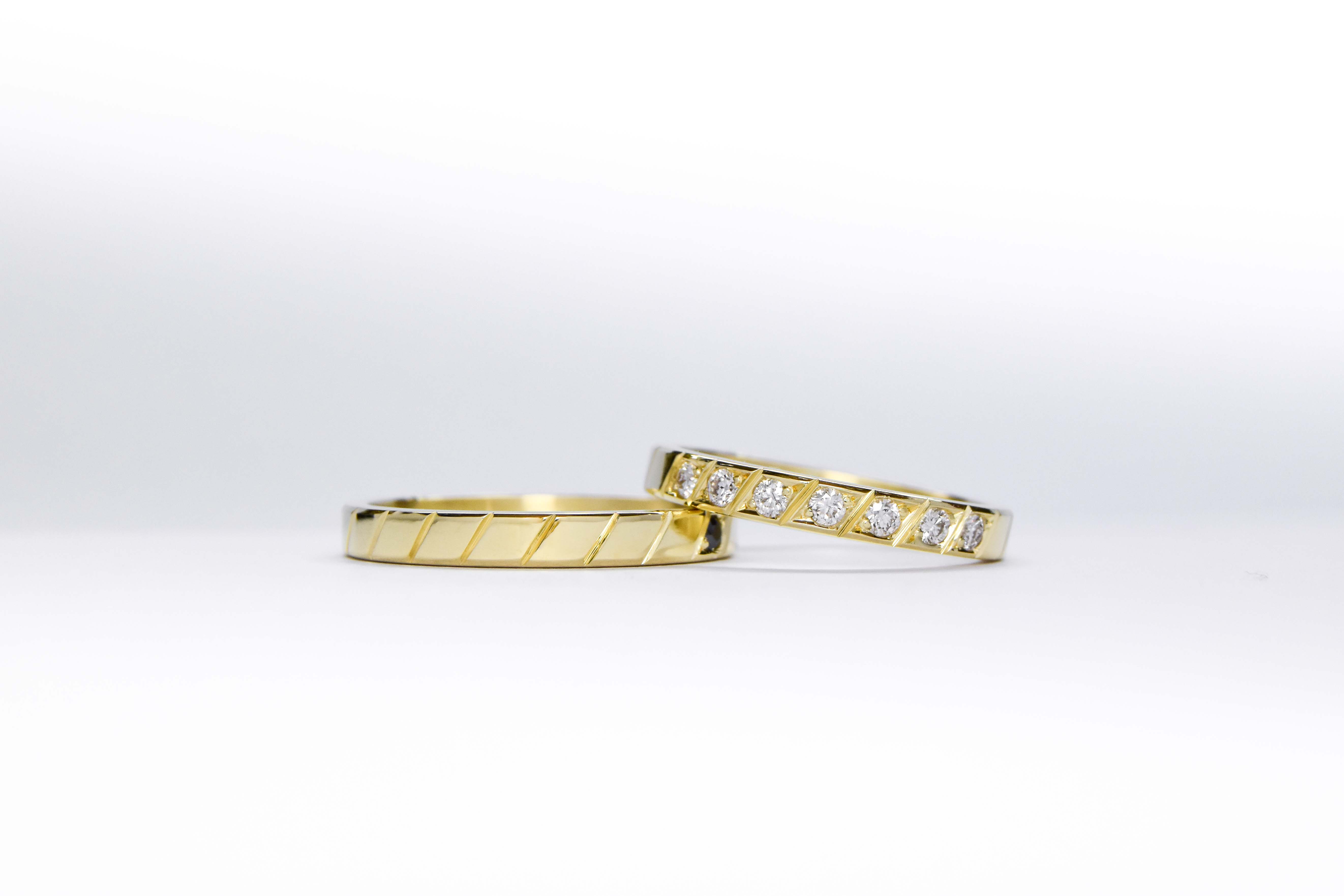 Alianzas de oro 18k amarillo con diamantes blancos engarzadas a mano sobre fondo blanco