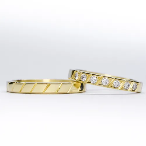 Alianzas de oro 18k amarillo con diamantes blancos engarzadas a mano sobre fondo blanco