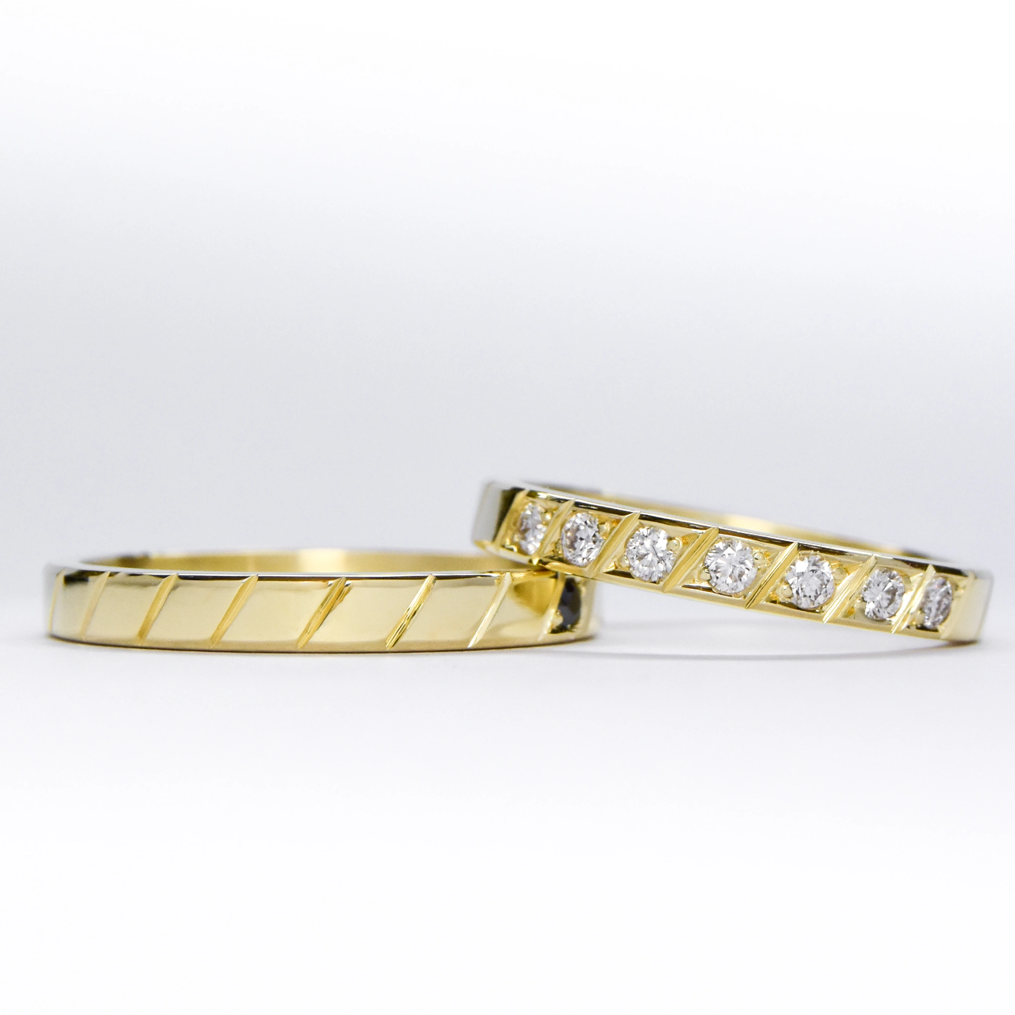 Alianzas de oro 18k amarillo con diamantes blancos engarzadas a mano sobre fondo blanco