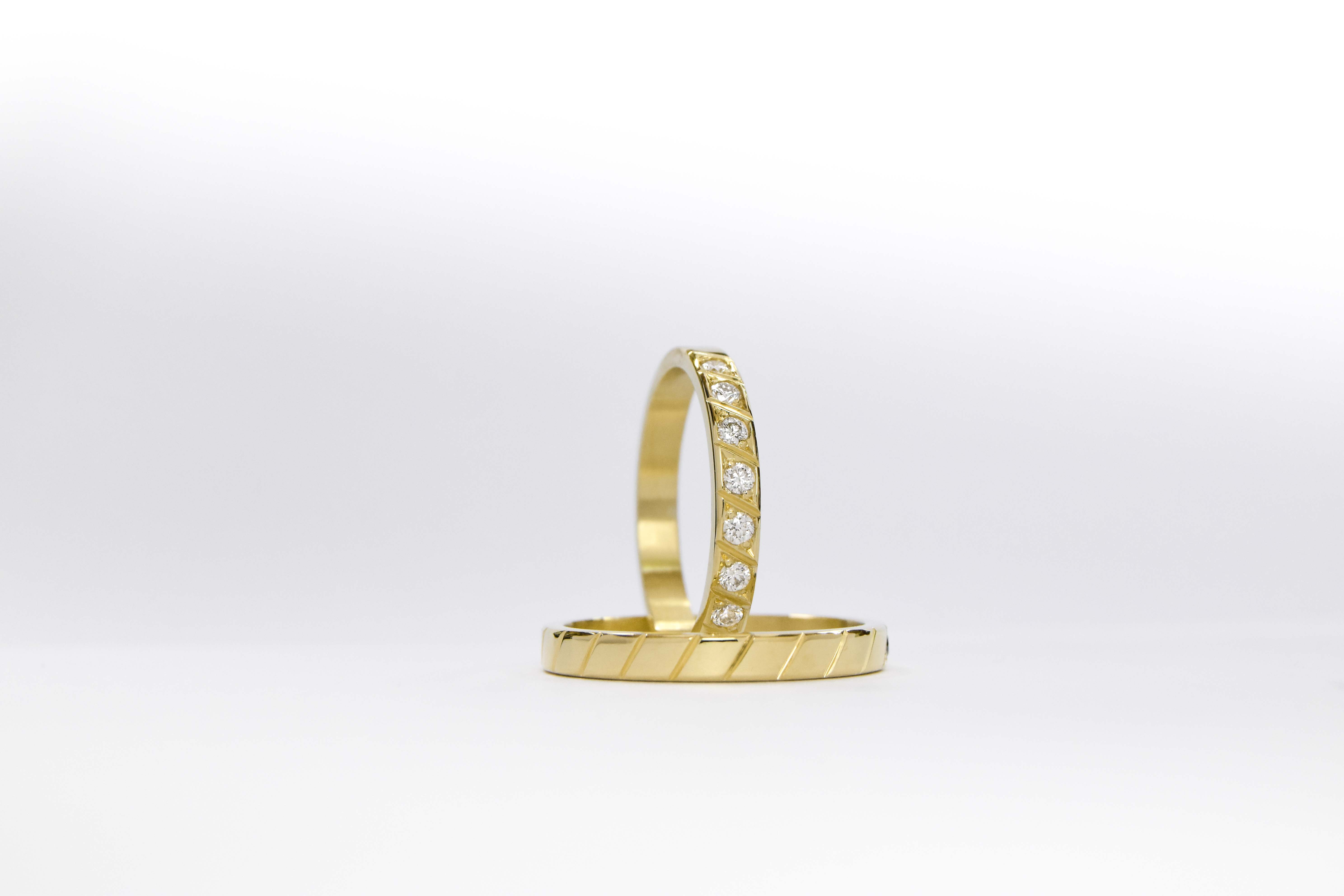 Alianzas de oro 18k amarillo con diamantes blancos engarzadas a mano sobre fondo blanco