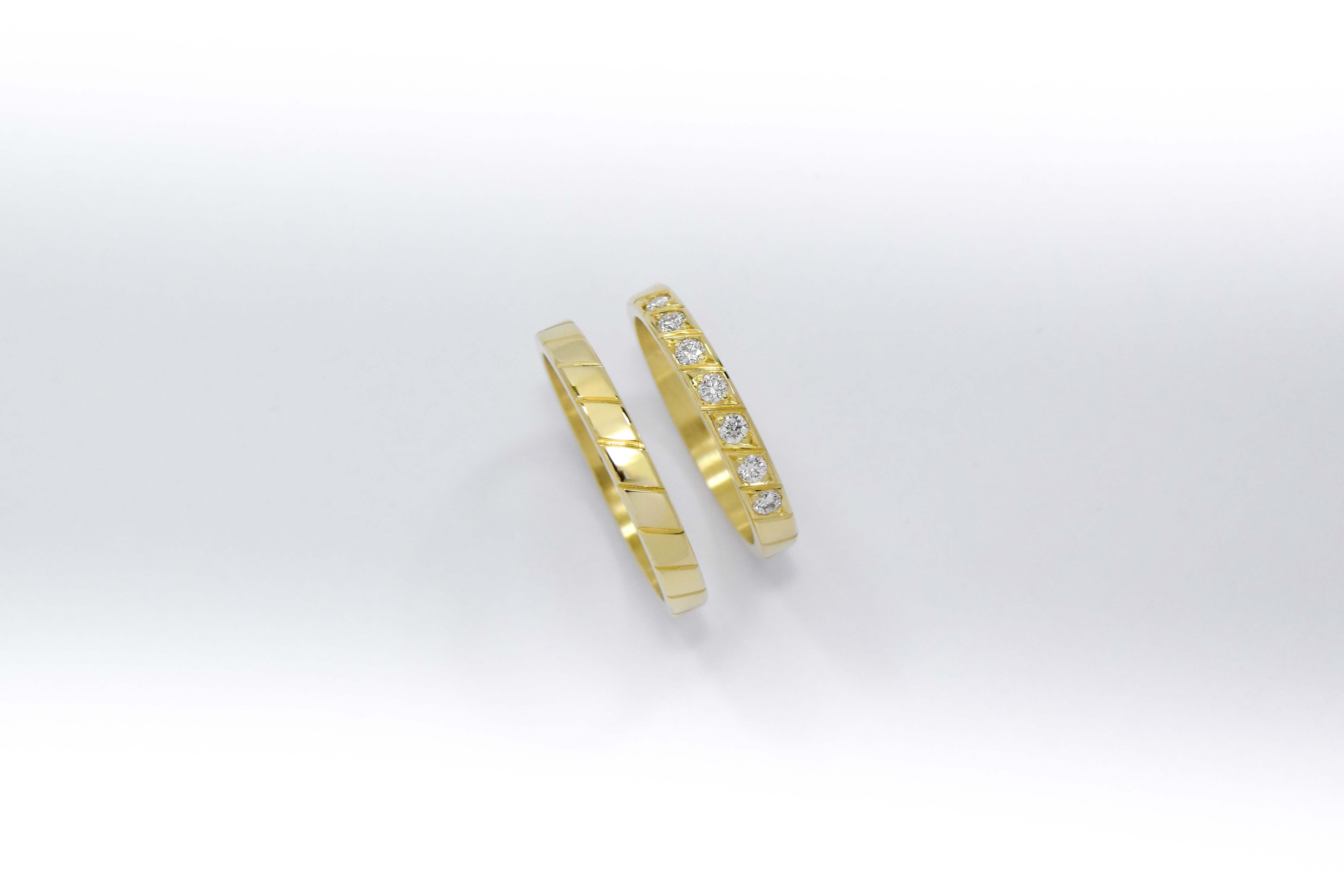 Alianzas de oro 18k amarillo con diamantes blancos engarzadas a mano sobre fondo blanco