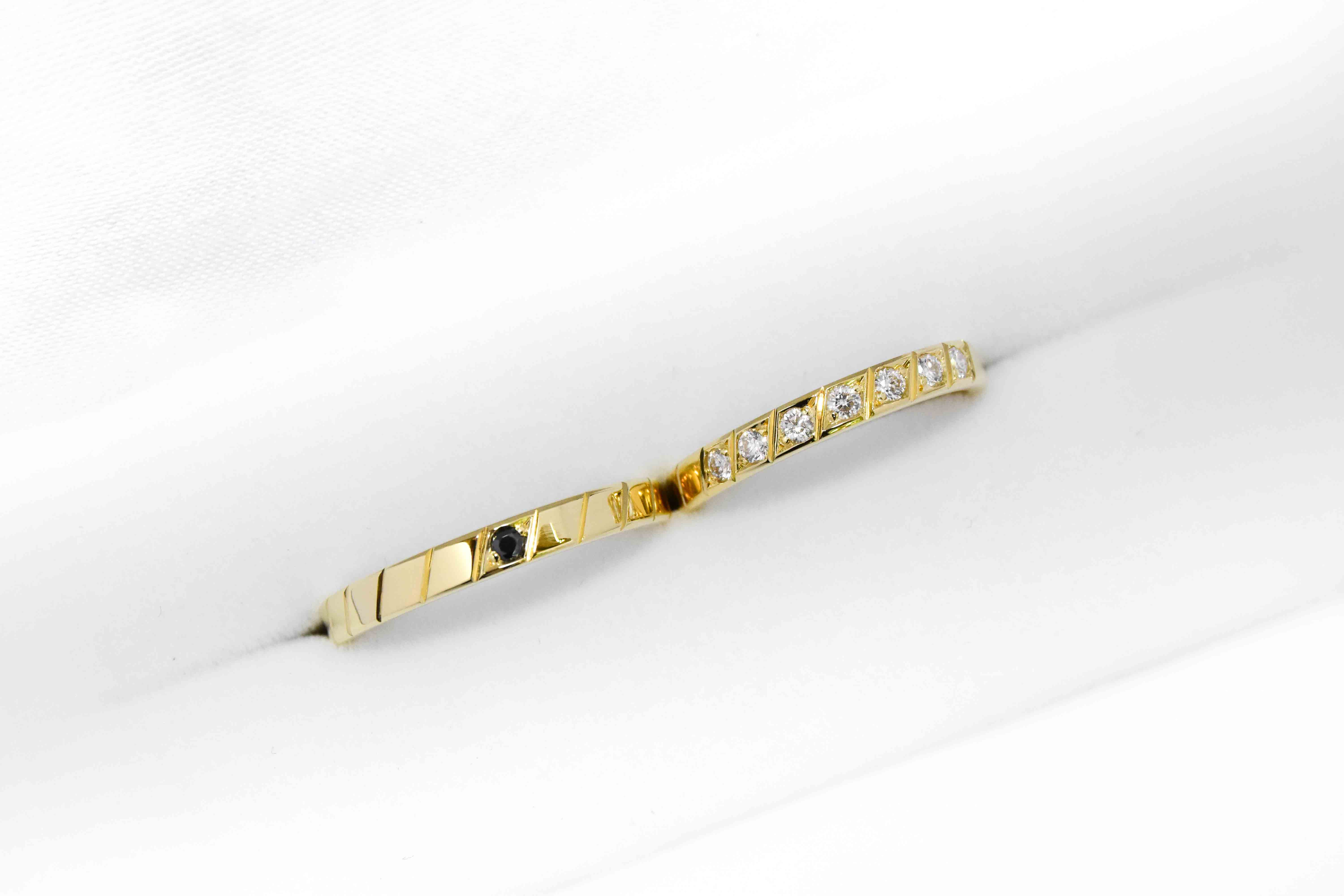 Alianzas de oro 18k amarillo con diamantes blancos engarzadas y gema negra a mano sobre fondo blanco