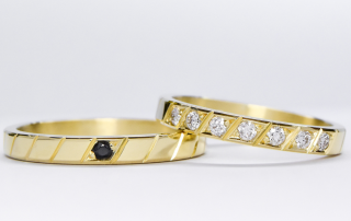 alianzas de oro 18k amarillo con diamantes y gemas engarzadas a mano sobre fondo blanco