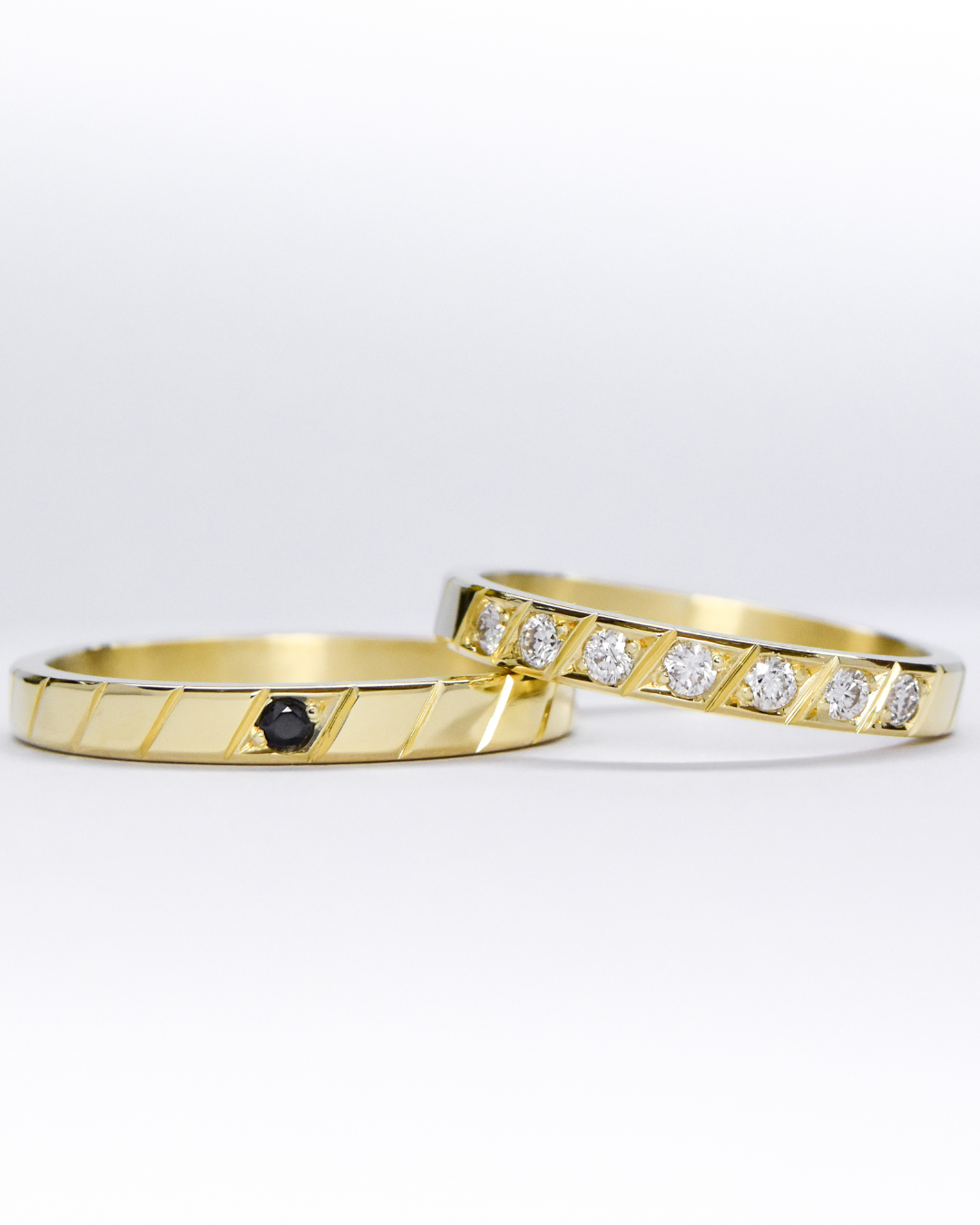 alianzas de oro 18k amarillo con diamantes y gemas engarzadas a mano sobre fondo blanco