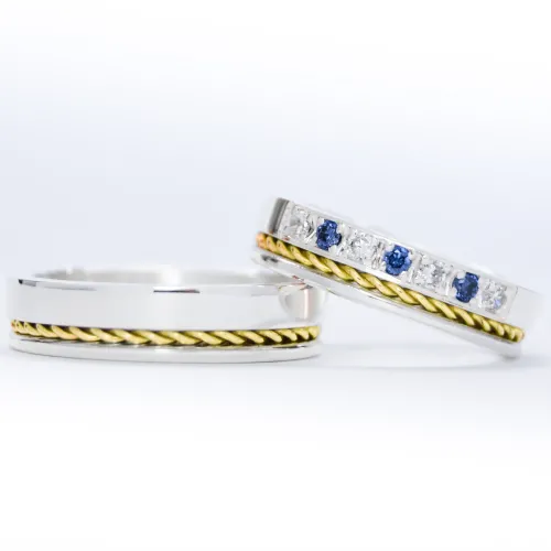 Alianzas de plata 950k y oro 18k amarillo con diamantes blancos y zafiros engarzadas. sobre fondo blanco.