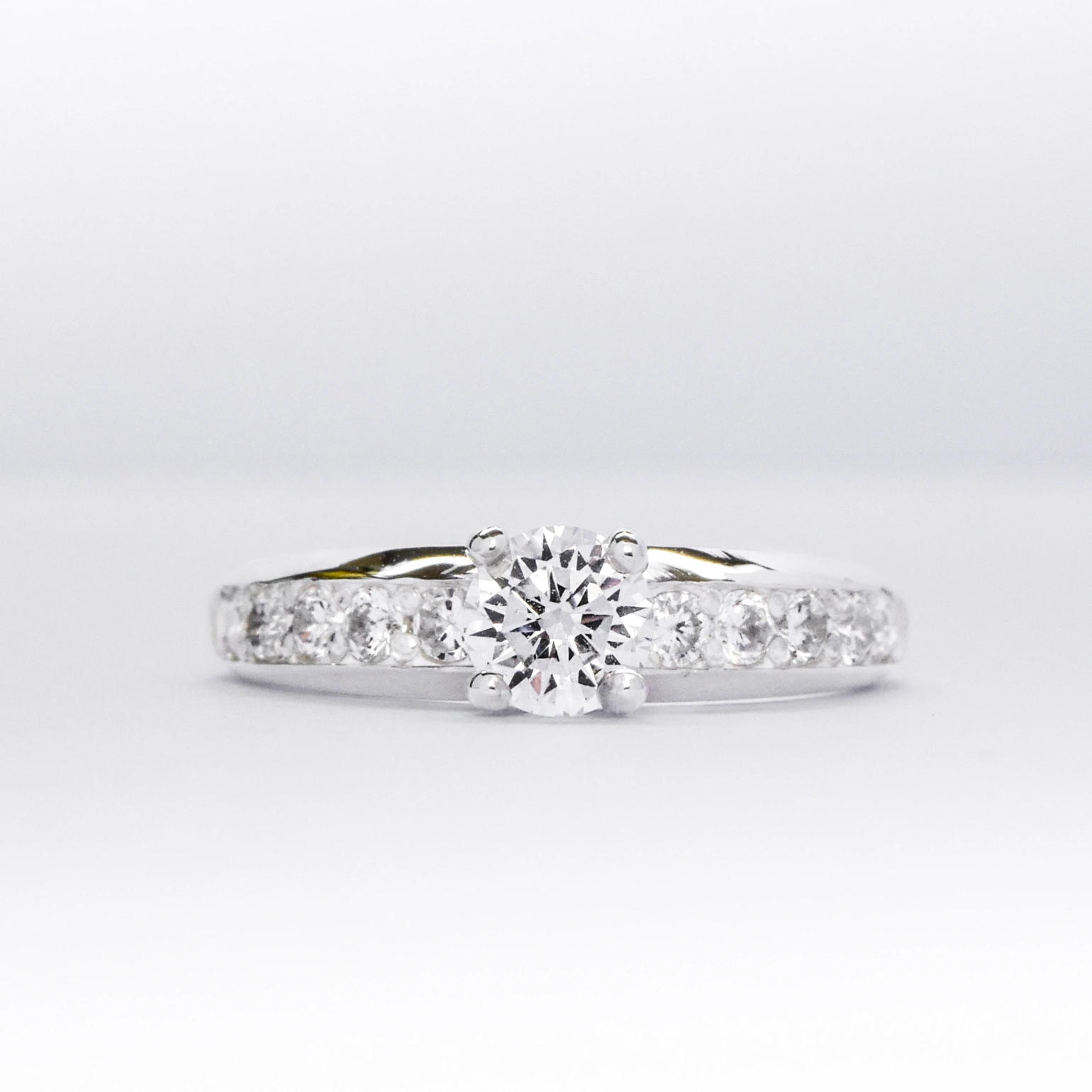 Anillo de compromiso de plata 925k con una gema blanca brillante y otras a los costados sobre fondo blanco