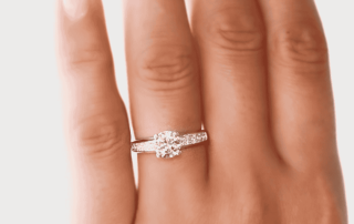 anillo de compromiso con una gema brillante colocada en la mano sobre fondo blanco