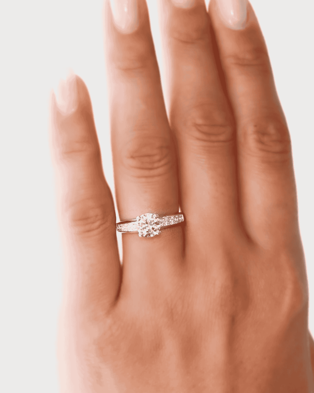 anillo de compromiso con una gema brillante colocada en la mano sobre fondo blanco