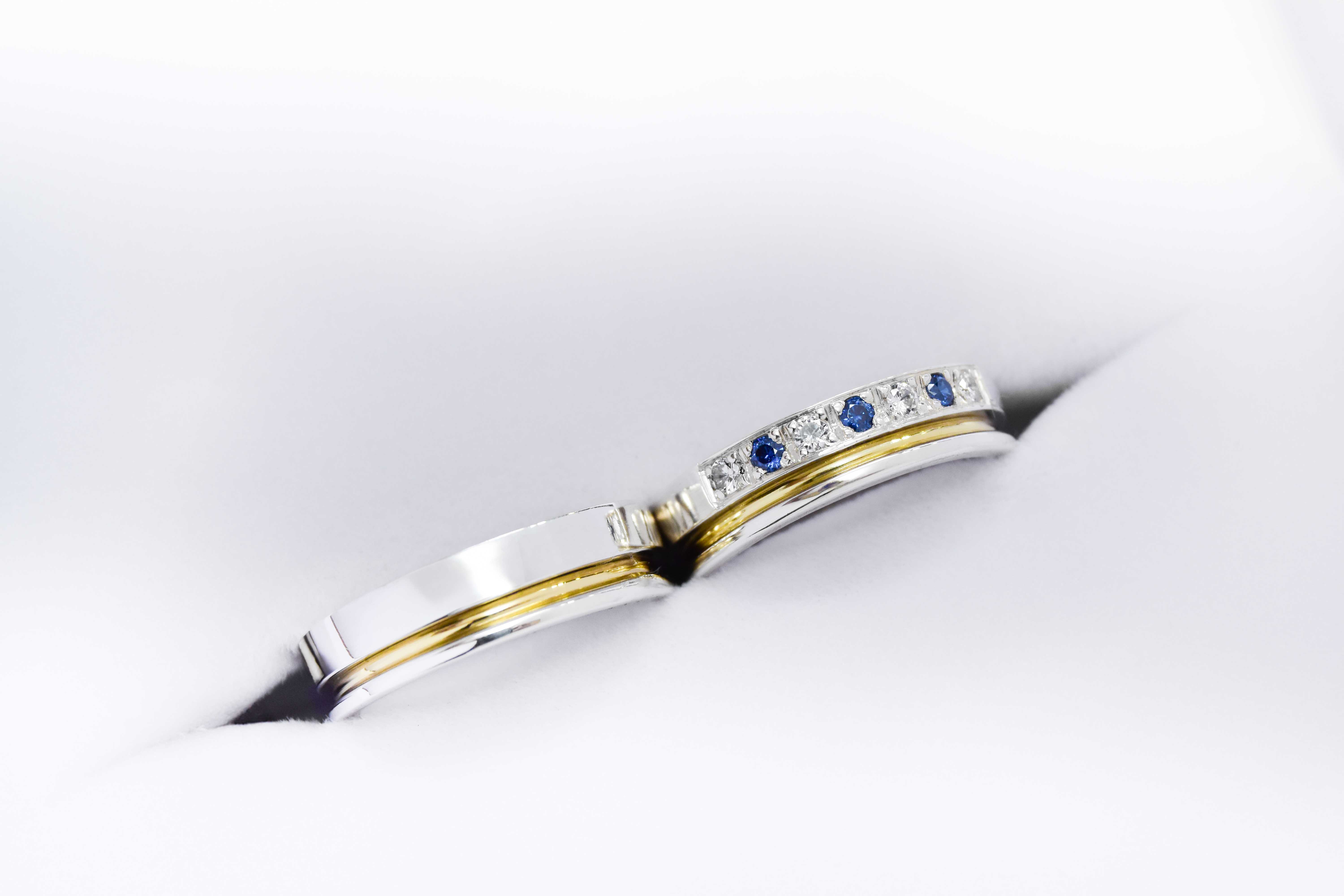 Alianzas de plata 950k y oro 18k amarillo con diamantes blancos y zafiros engarzadas. sobre fondo blanco.