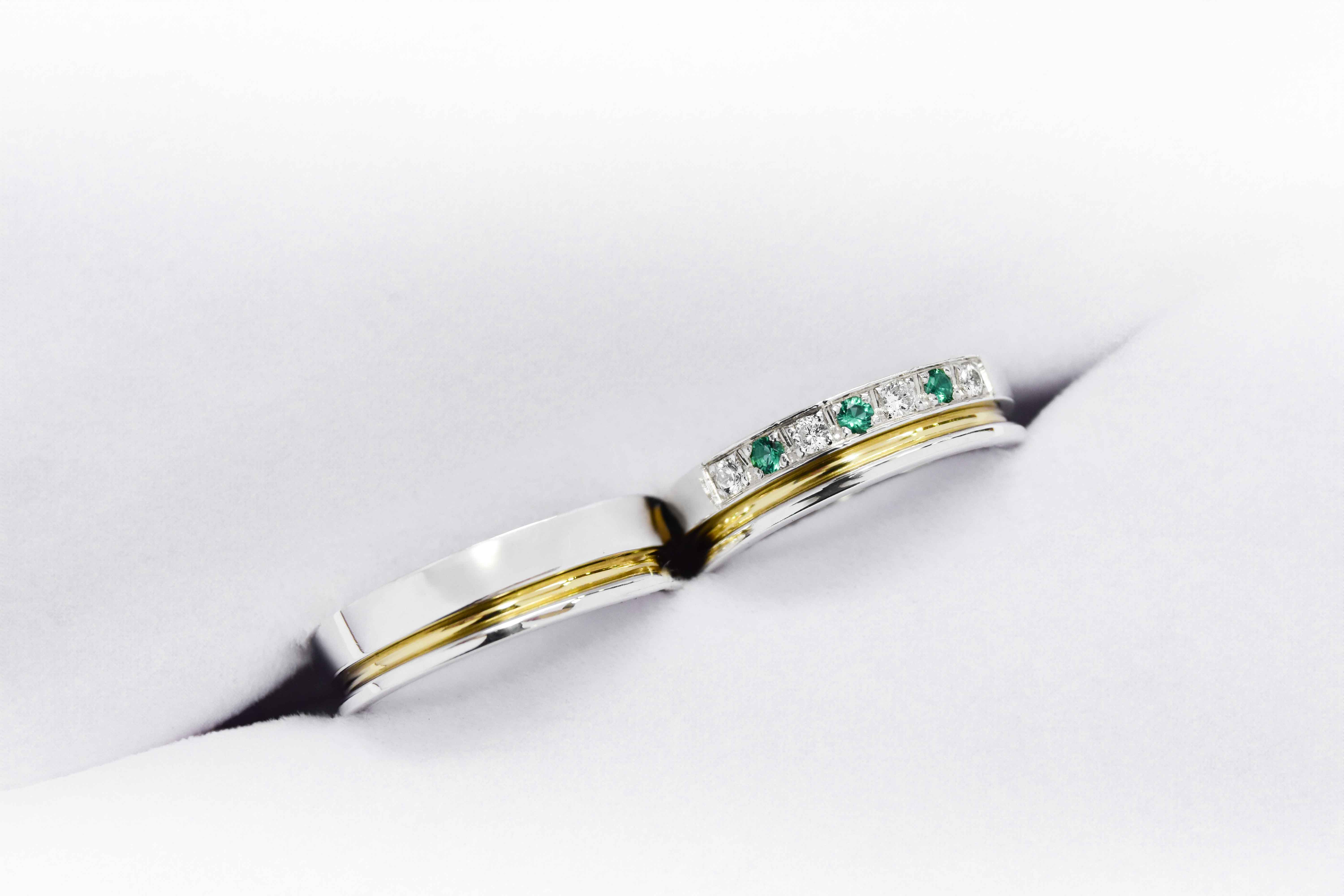Alianzas de plata 950k y oro 18k amarillo con diamantes blancos y esmeraldas engarzadas. sobre fondo blanco.