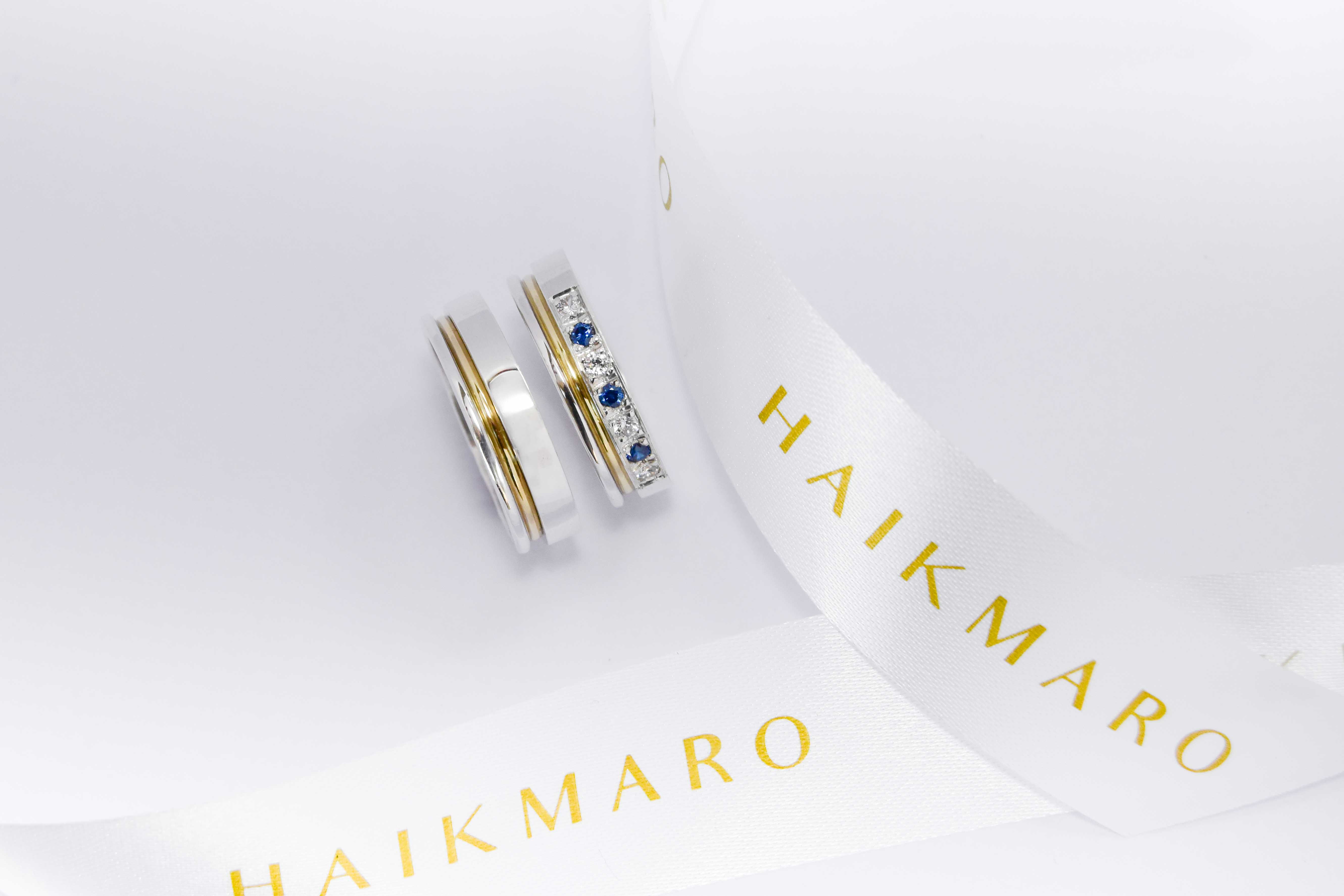 Alianzas de plata 950k y oro 18k amarillo con diamantes blancos y zafiros engarzadas. sobre fondo blanco.