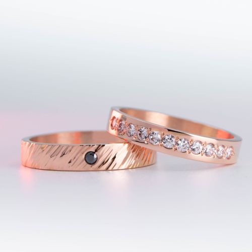 alianzas de oro 18k rojo con diamantes blancos engarzadas y gema negra a mano sobre fondo blanco
