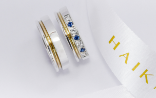 Alianzas de plata 950k y oro 18k amarillo con diamantes blancos y zafiros engarzadas. sobre fondo blanco.