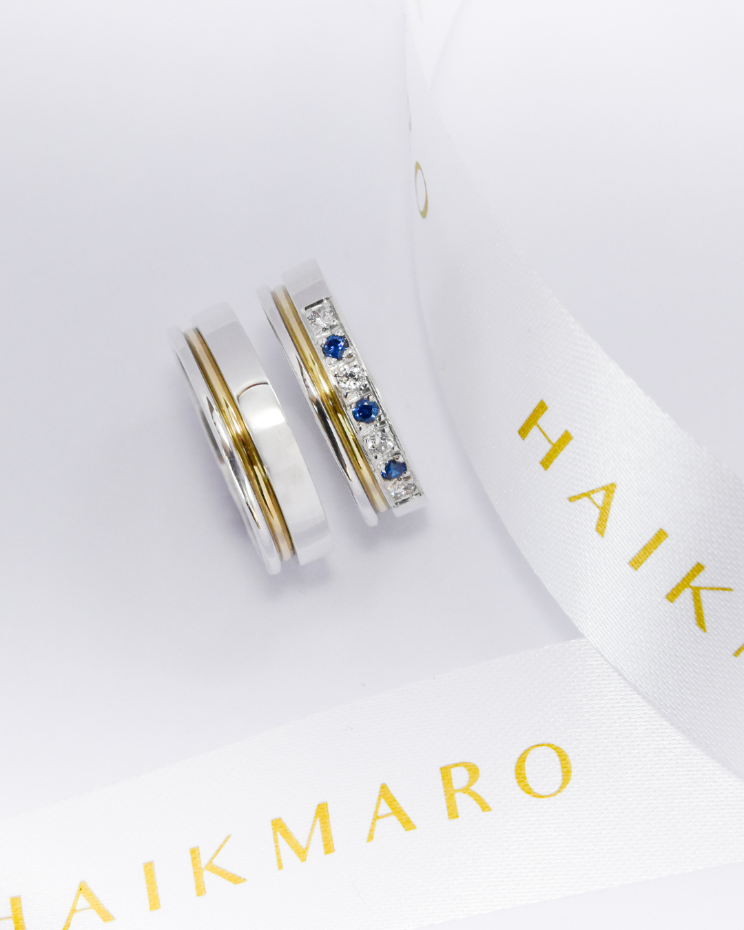 Alianzas de plata 950k y oro 18k amarillo con diamantes blancos y zafiros engarzadas. sobre fondo blanco.
