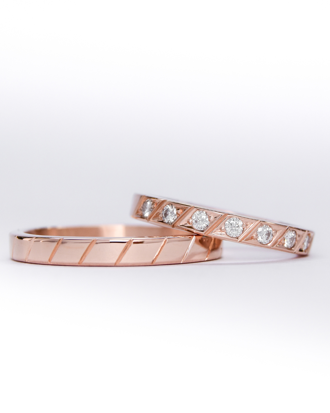 alianzas de oro 18k rosa con diamantes blancos engarzadas a mano sobre fondo blanco