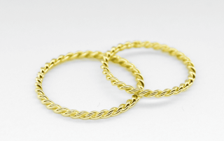 Anillos de oro amarillo 18K tipo trenza sobre fondo blanco