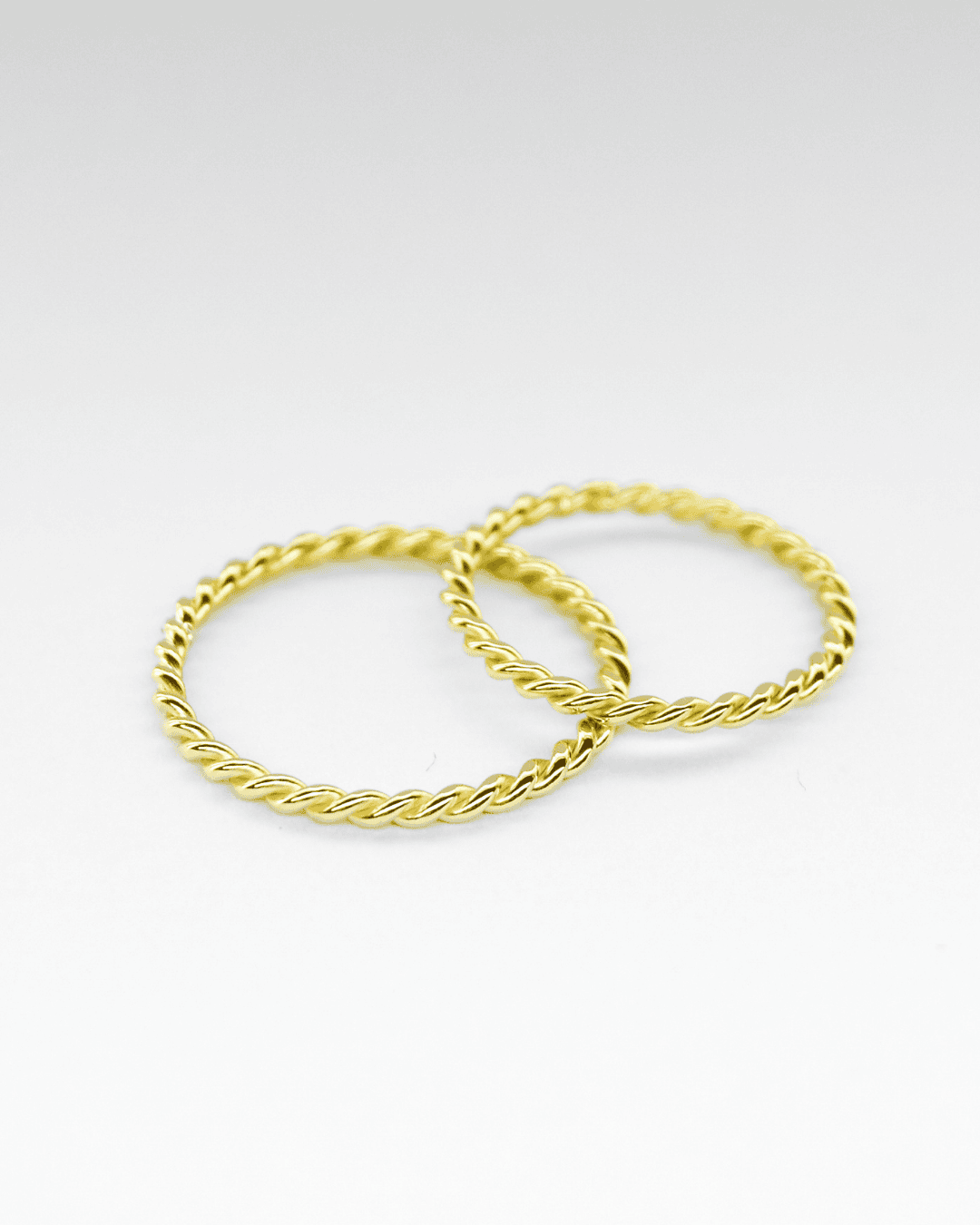 Anillos de oro amarillo 18K tipo trenza sobre fondo blanco