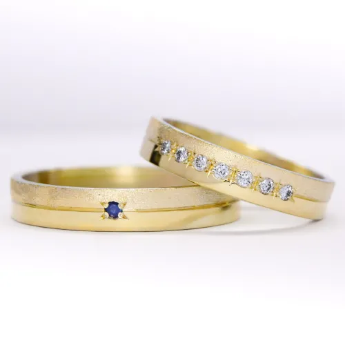 alianzas de oro 18k amarillo con diamantes y gemas engarzadas a mano sobre fondo blanco