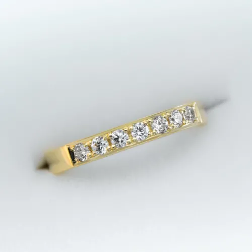 Anillo de oro estilo Medio Sin FIn con 7 gemas engarzadas en una fila sobre fondo blanco