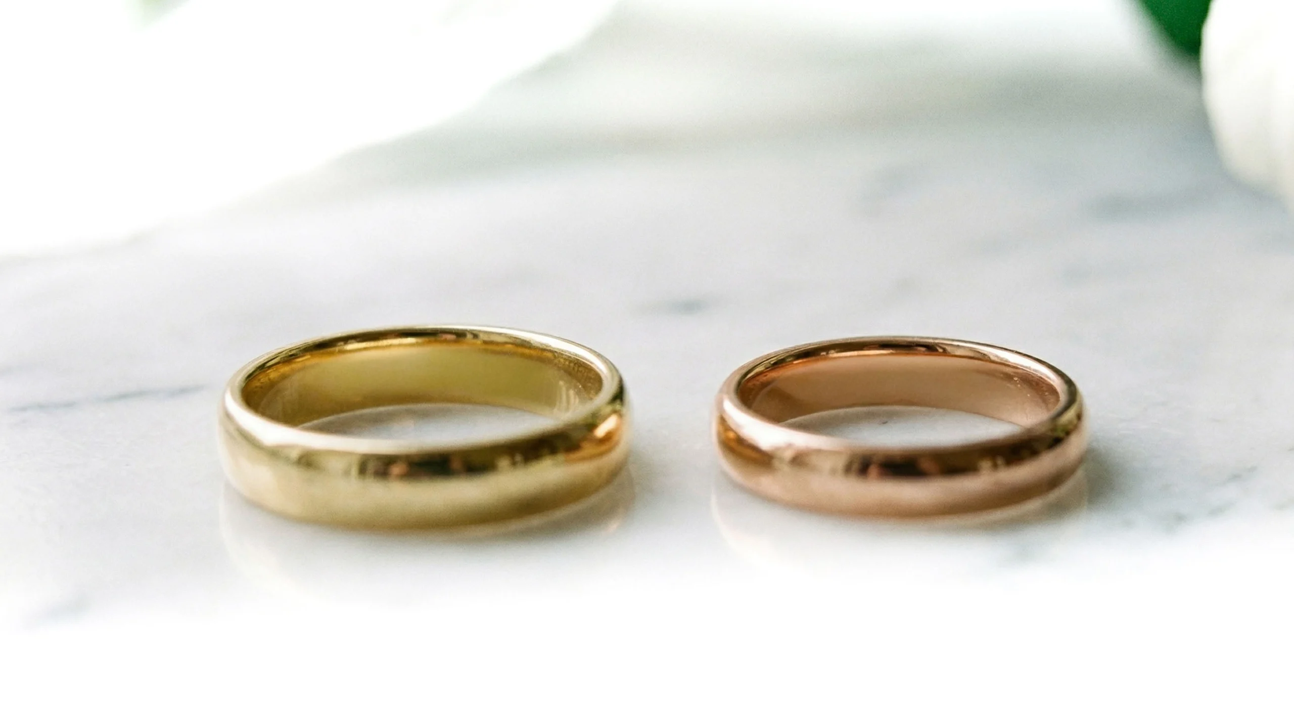 Alianzas de oro amarillo y oro rosa sobre superficie de mármol