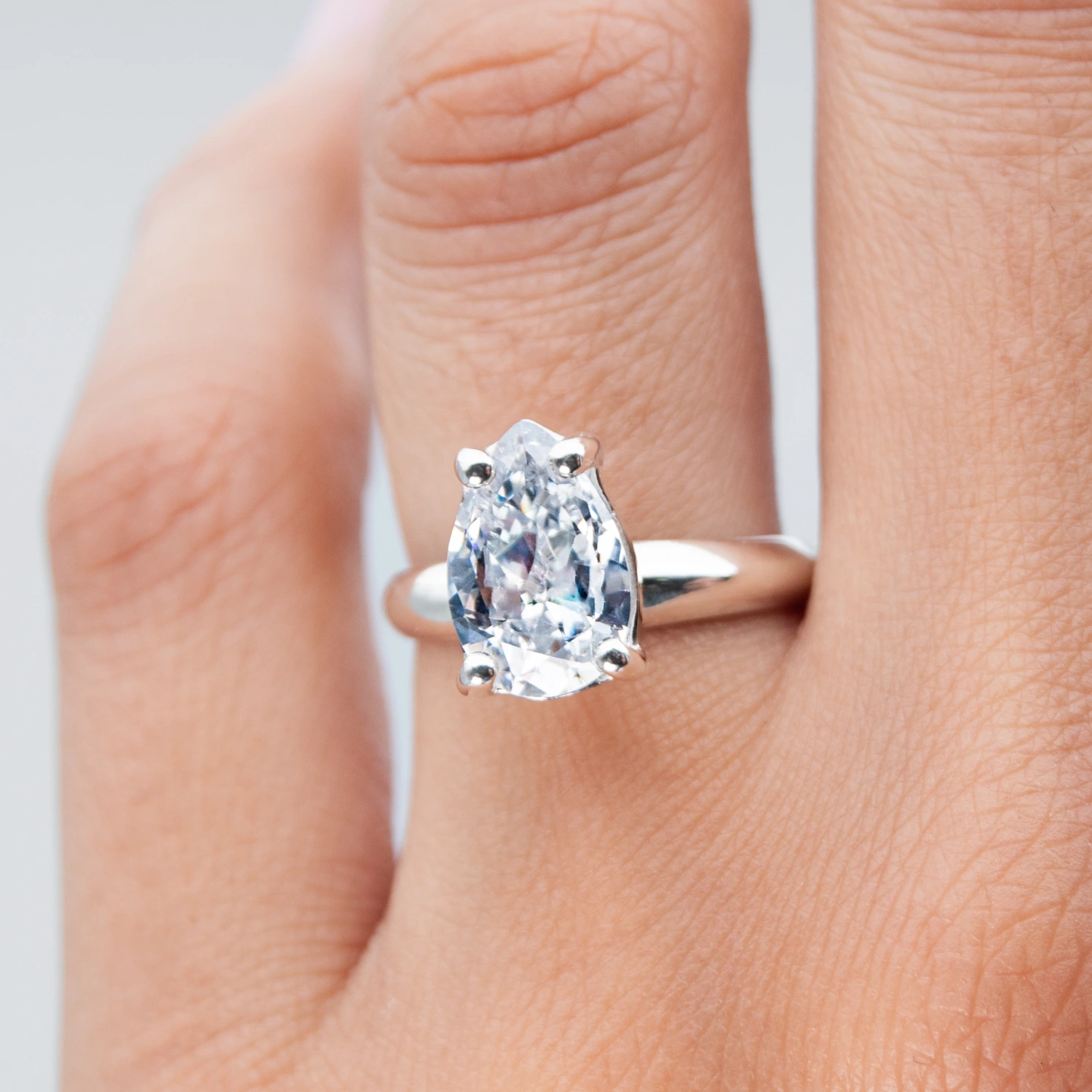 Anillo de plata con una gema Pear Cut sobre el dedo