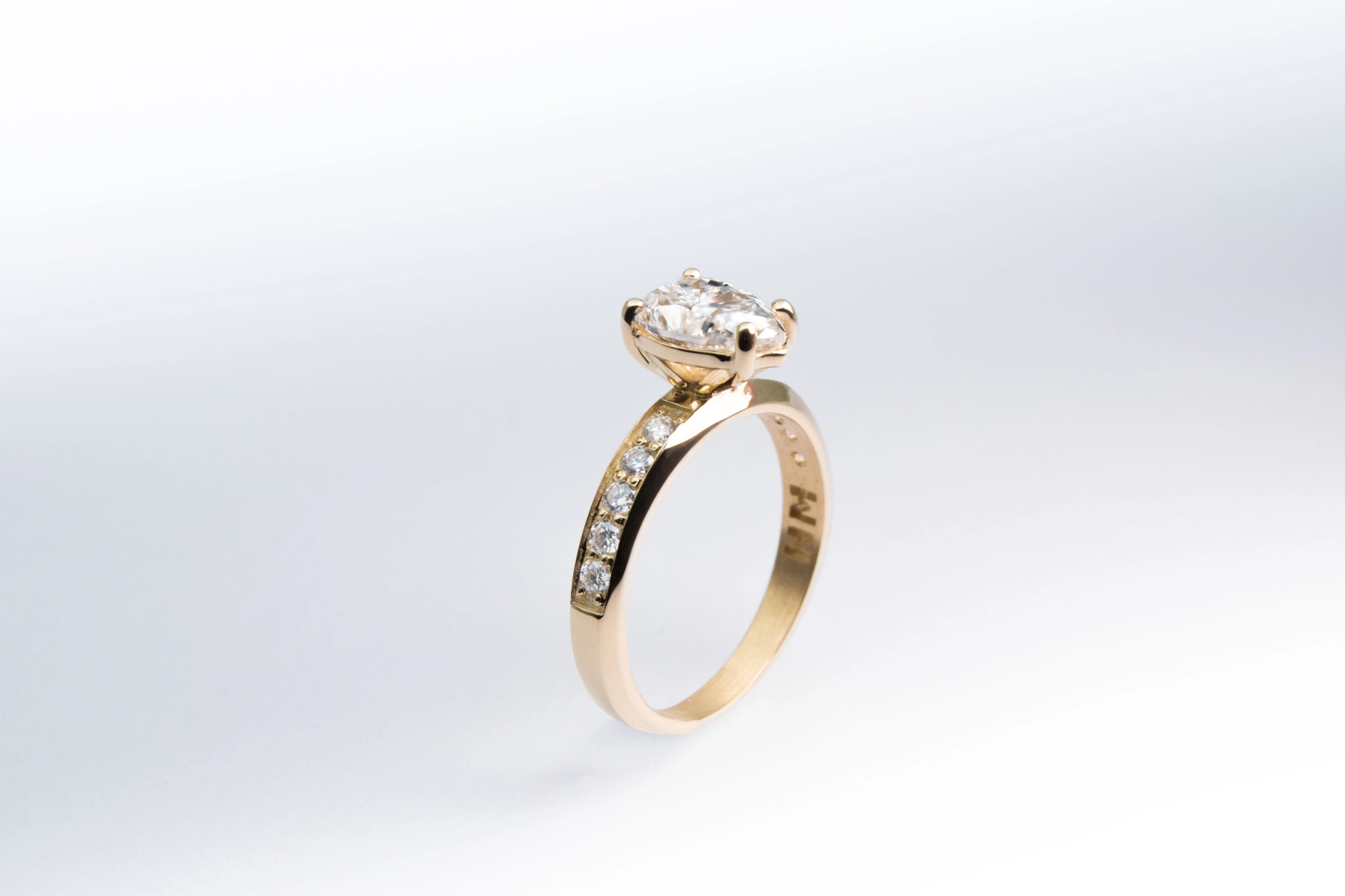 anillo de compromiso de oro modelo Taylor más con gema pear cut sobre fondo blanco