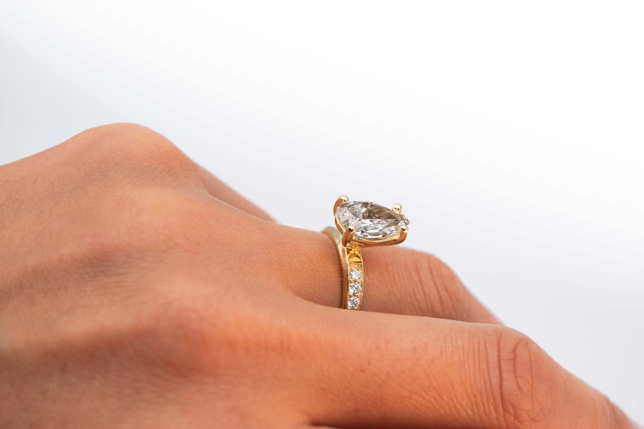 anillo de compromiso de oro modelo Taylor Max con gema pear cut en la mano de la modelo