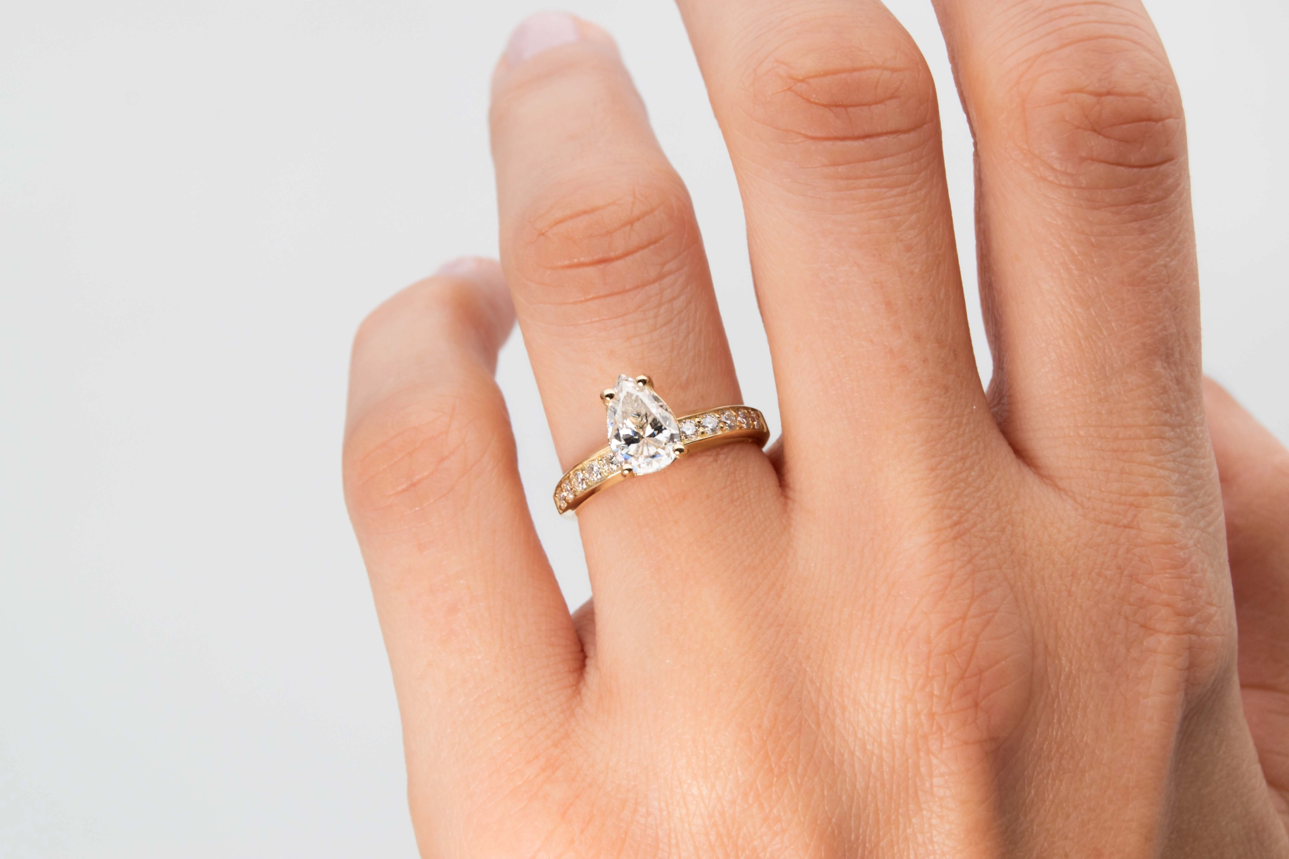 anillo de compromiso de oro modelo Taylor con gema pear cut en la mano de la modelo