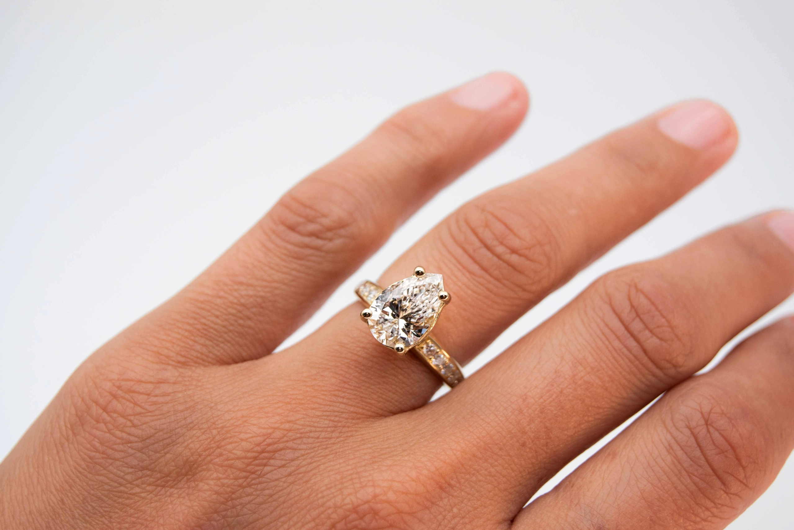 anillo de compromiso de oro modelo Taylor Max con gema pear cut en la mano de la modelo