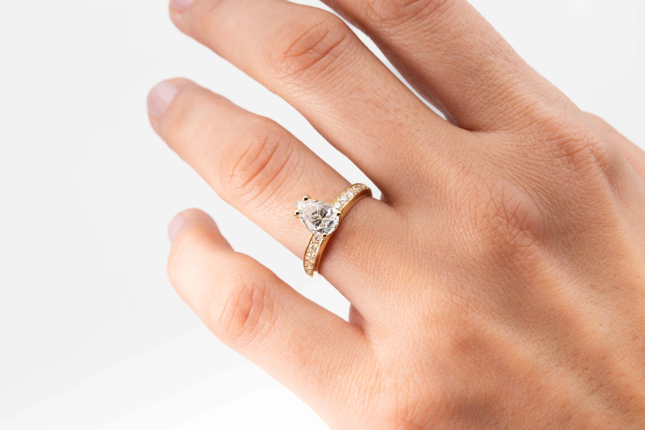 anillo de compromiso de oro modelo Taylor con gema pear cut en la mano de la modelo