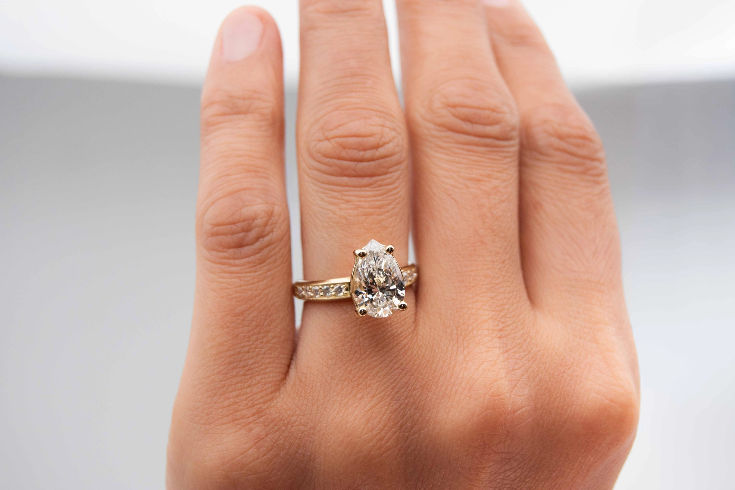 anillo de compromiso de oro modelo Taylor Max con gema pear cut en la mano de la modelo