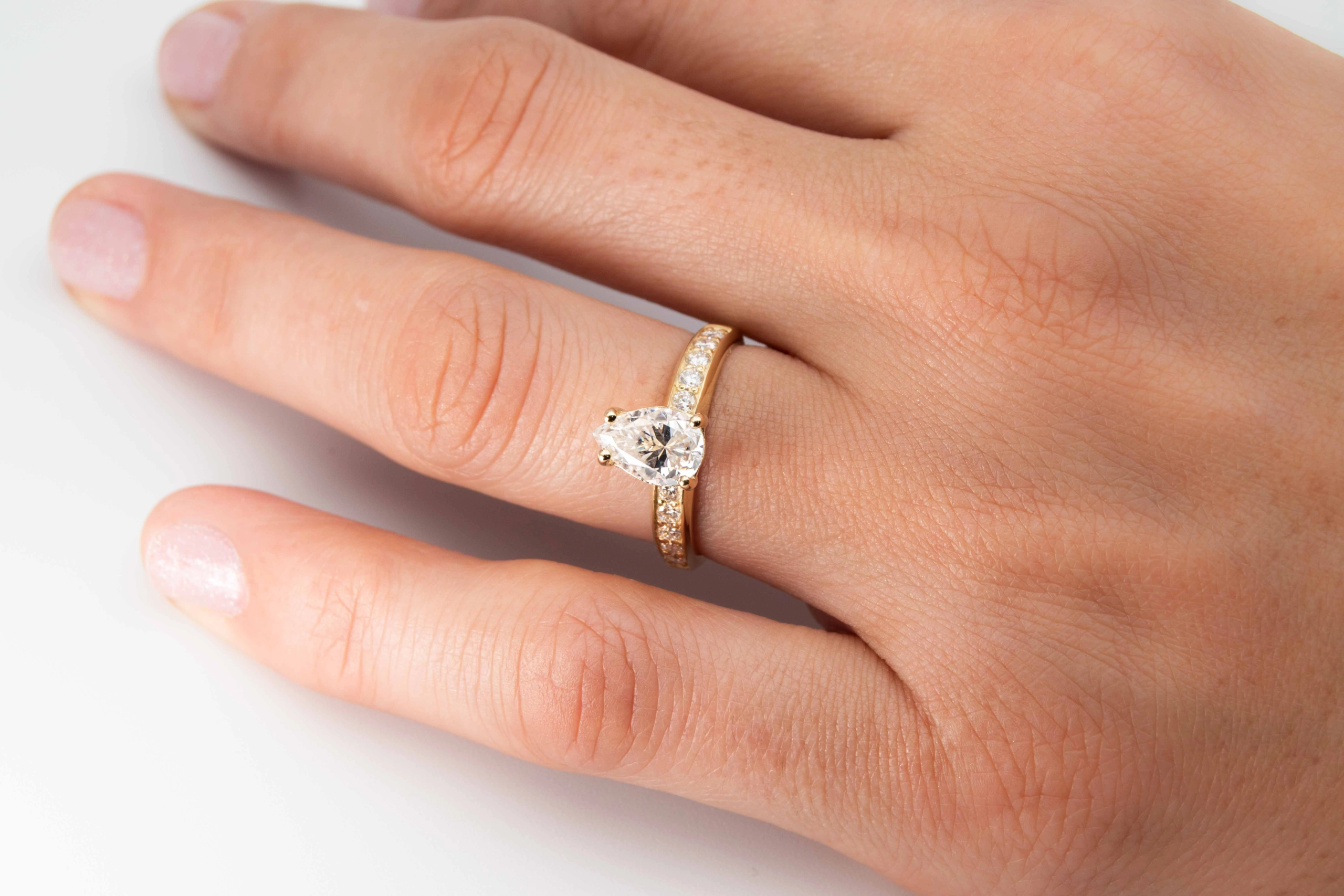 anillo de compromiso de oro modelo Taylor con gema pear cut en la mano de la modelo
