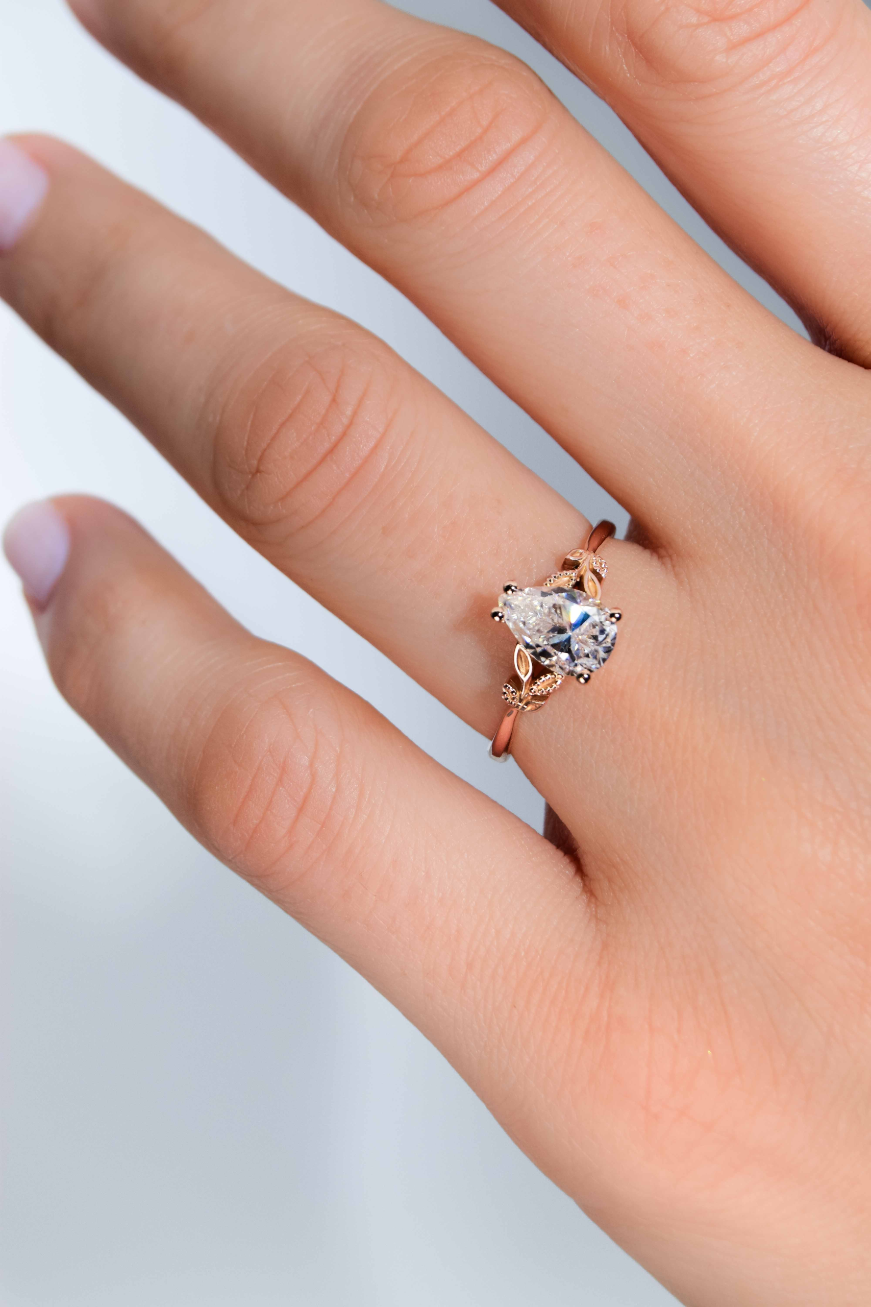anillo de compromiso de oro modelo Taylor con gema pear cut en la mano de la modelo