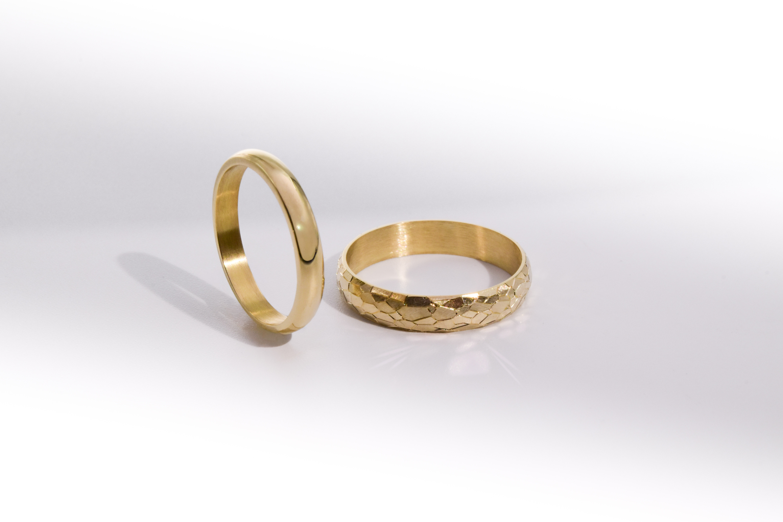 Alianzas de casamiento de oro 18K con textura de diferentes anchos modelo Perseo sobre fondo blanco