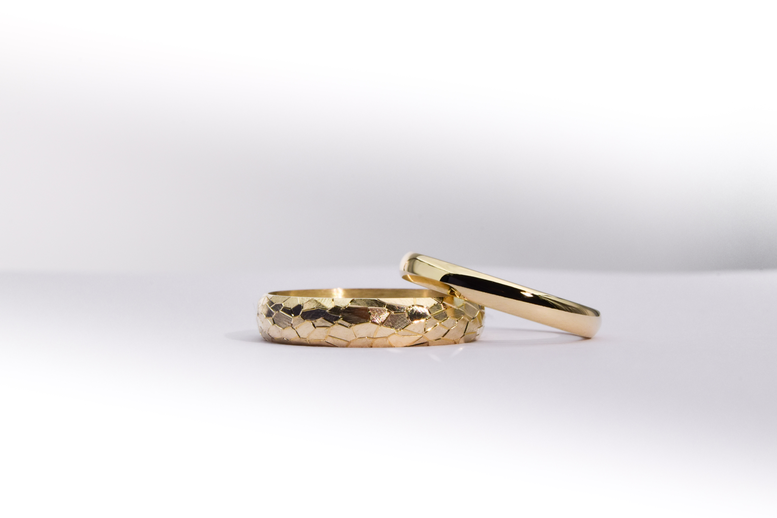 Alianzas de casamiento de oro 18K con textura de diferentes anchos modelo Perseo sobre fondo blanco